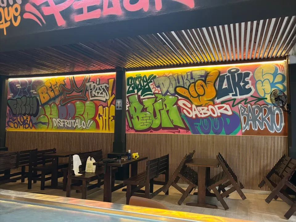 Mural de letras de colores a lo largo de la pared de un bar, bajo una luz amarilla
