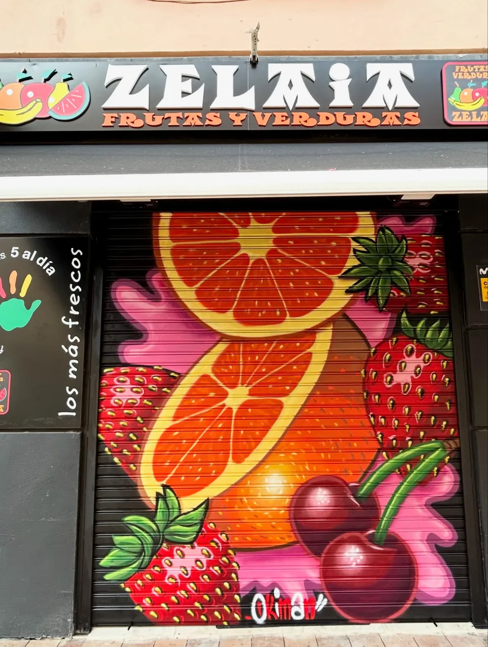 Persiana de una frutería pintada con naranjas, fresas y cerezas
