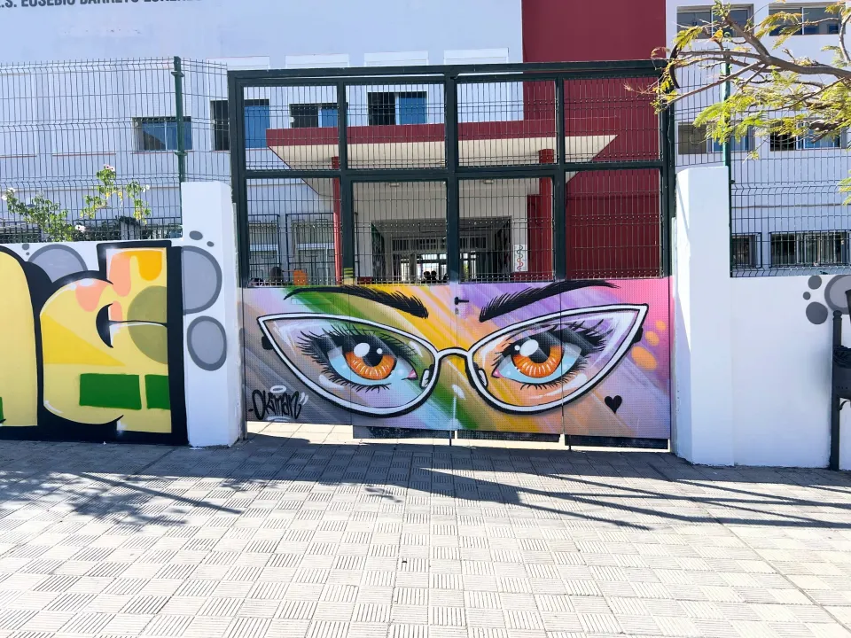 Portón de un instituto pintado con unos ojos con gafas y colores del arcoíris