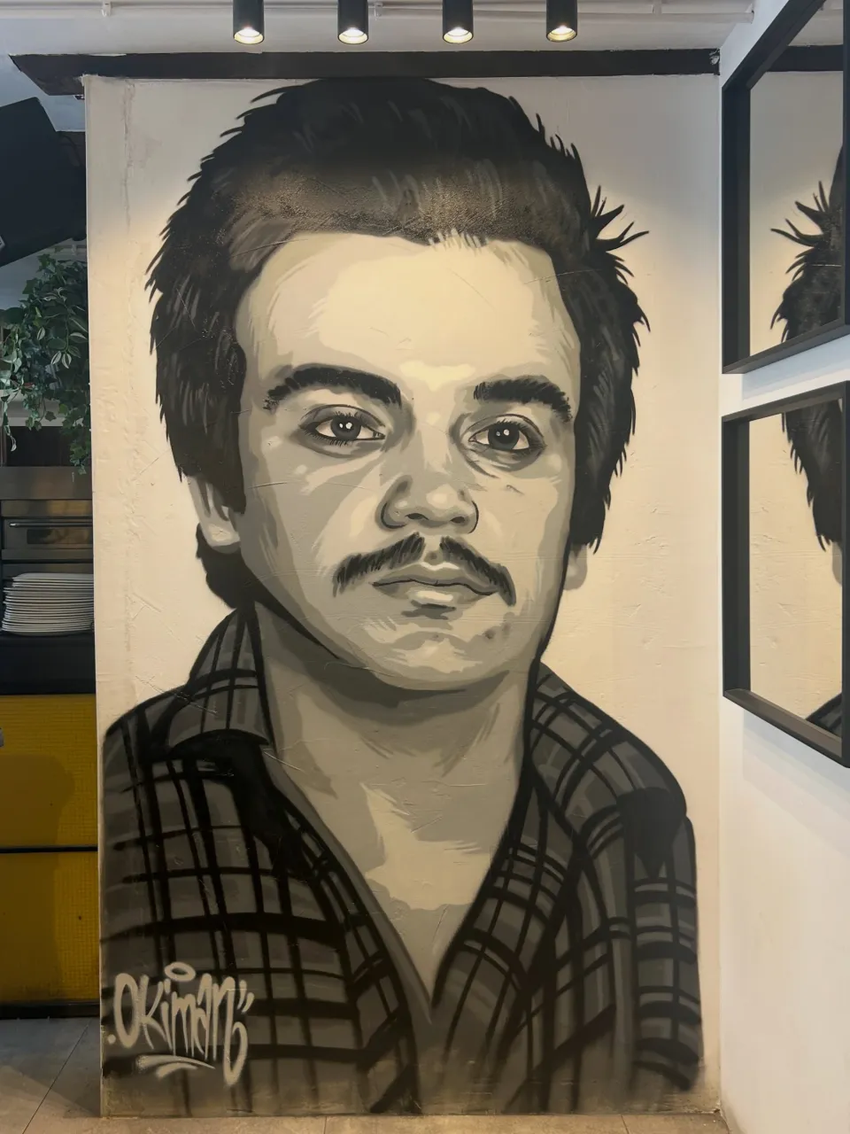 Retrato en blanco y negro de un hombre con bigote pintado en la pared de un local