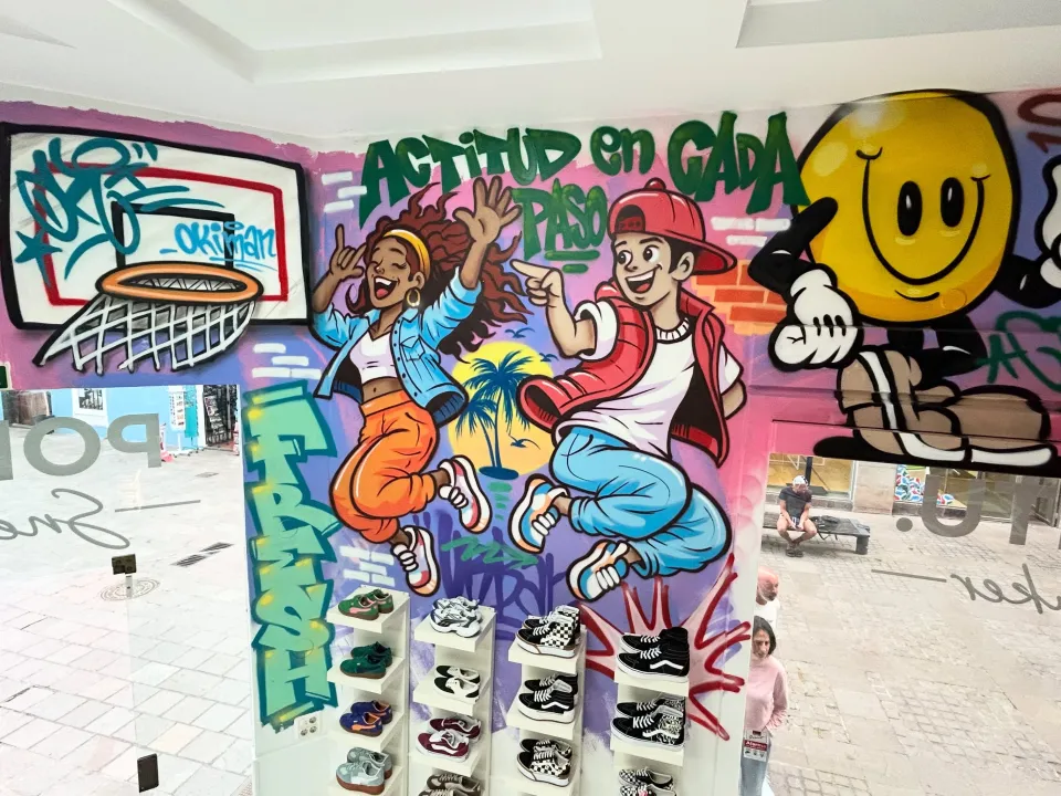Mural en una tienda de zapatillas con dos jóvenes saltando, una canasta y una cara sonriente